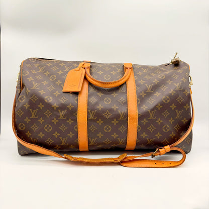 Sac de voyage Louis Vuitton Keepall Bandoulière 50 en toile Monogram, vue de face avec sangle et étiquette porte-adresse