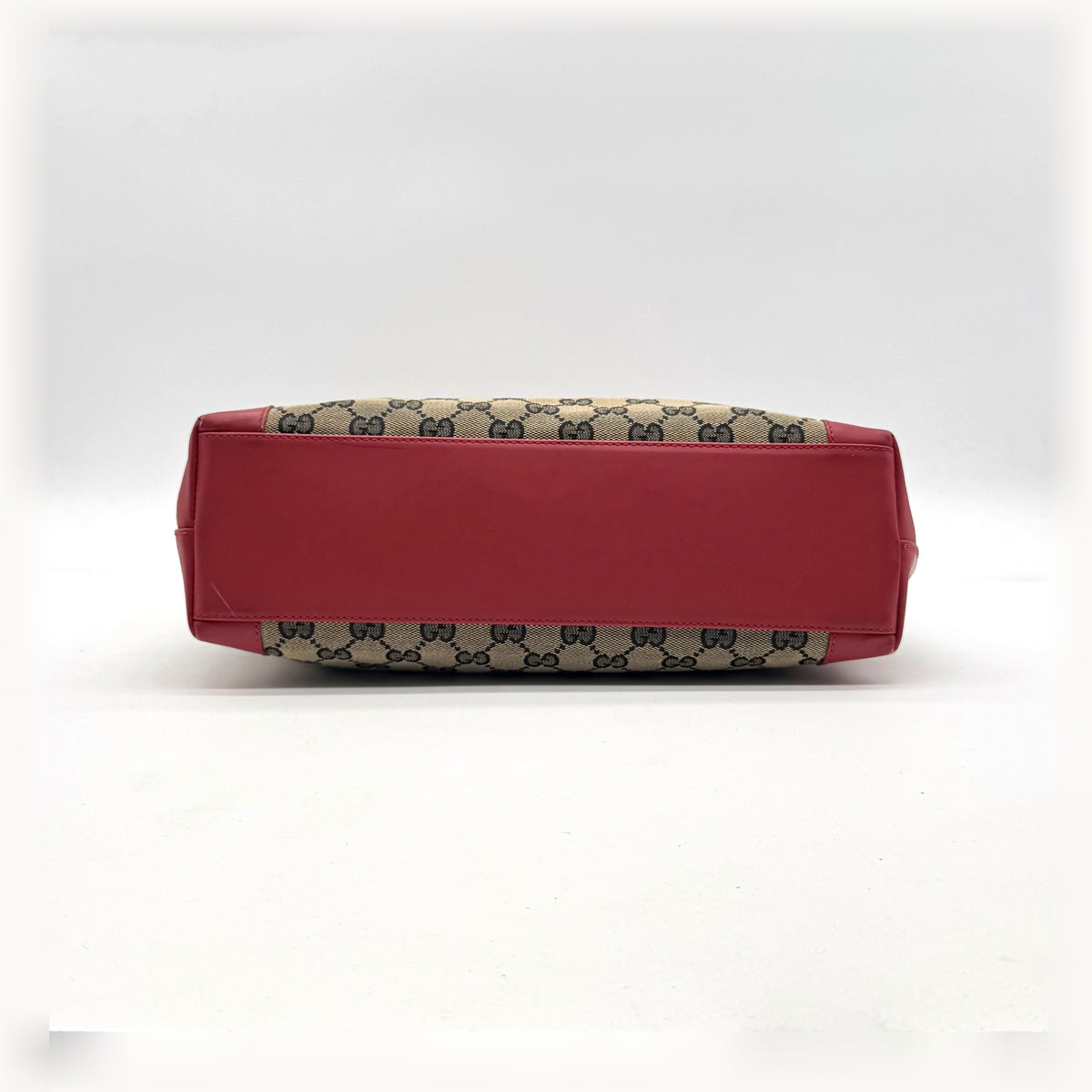Gucci Tote Lona GG y Piel Roja - bolso apoyado en plano, canto y base de piel