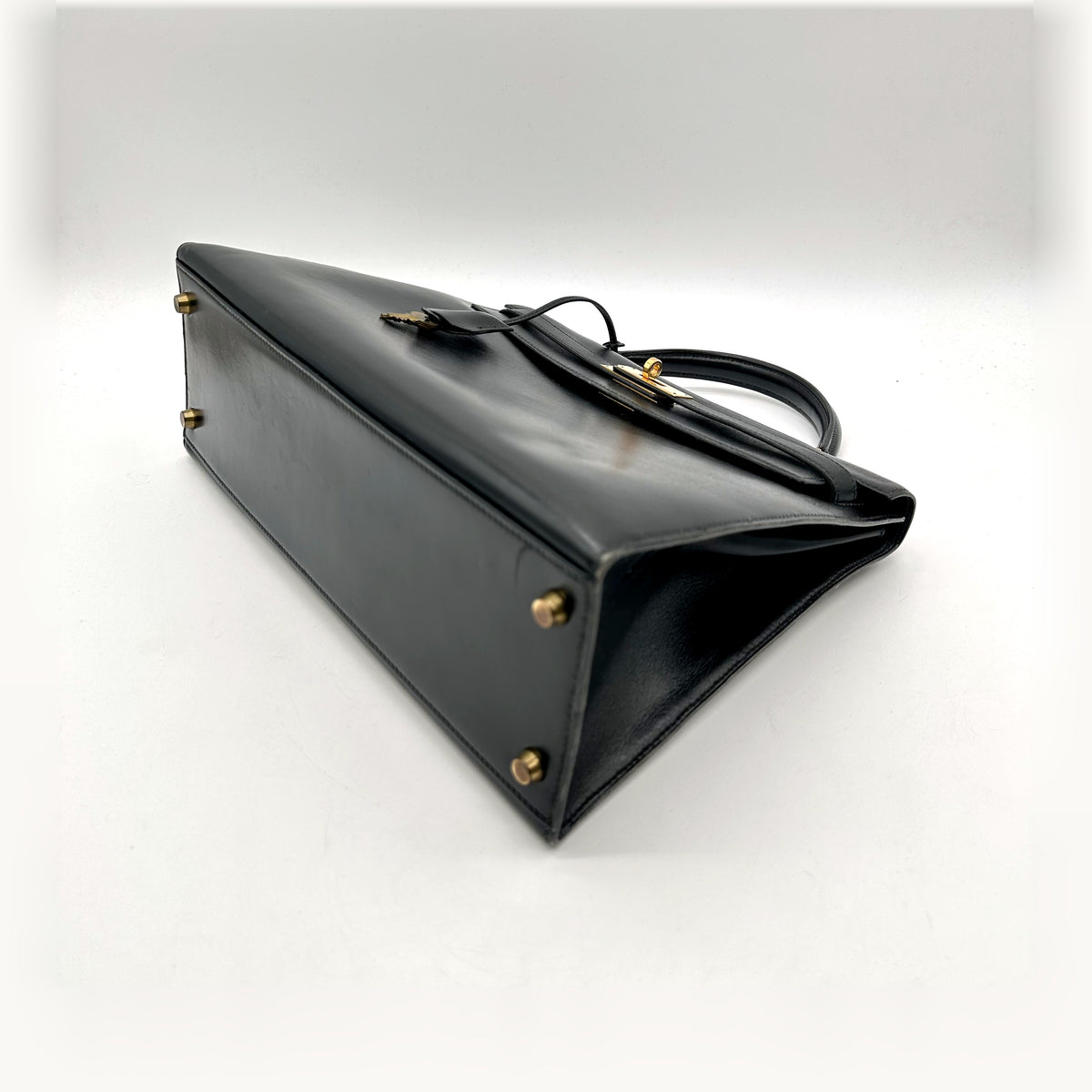 Hermès Kelly 32 Cuir Box Calf Noir - vue du dessous en angle, clous de base