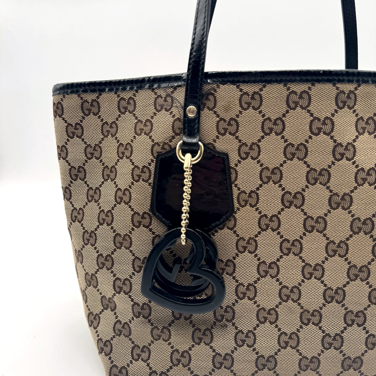 Gucci Tote Toile GG Beige et Cuir Verni Noir - détail de la breloque cœur sur sa chaînette