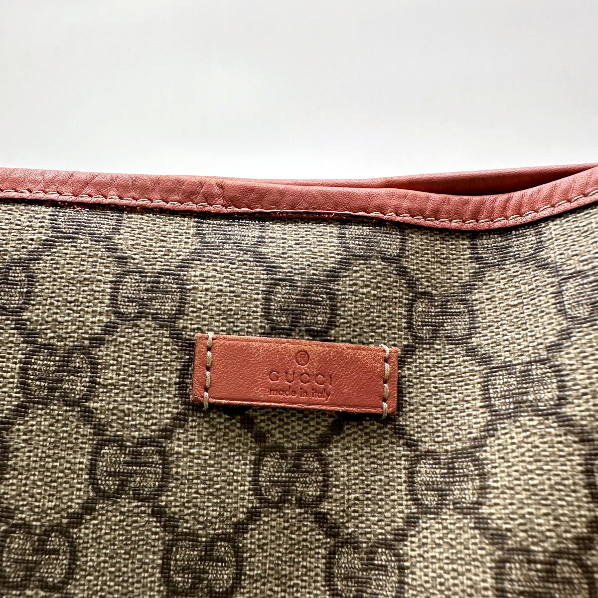 Gucci Tote Toile GG Beige et Cuir Corail - détail de la patte de cuir Gucci en façade