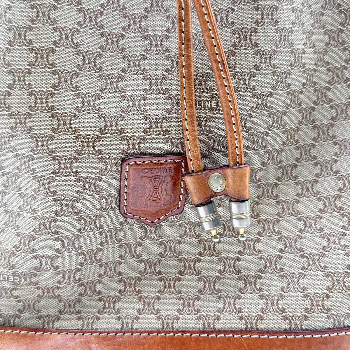 Céline Seau Toile Macadam Beige - détail de l'écusson de cuir et des embouts du cordon