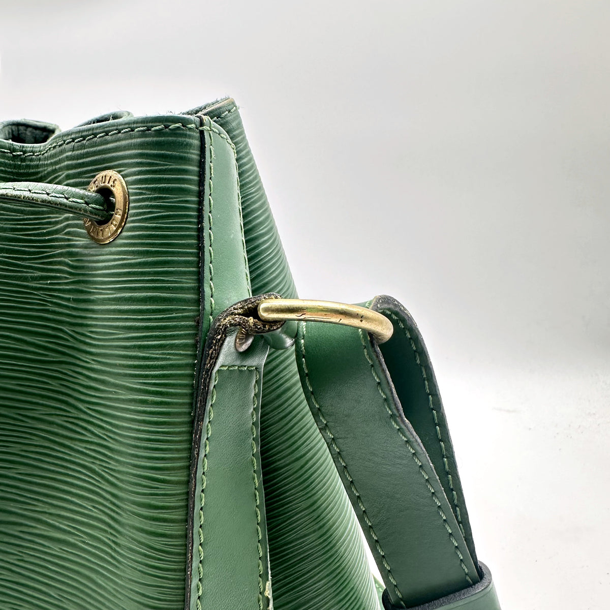 Louis Vuitton Petit Noé Cuir Épi Vert - détail des œillets et de la boucle dorée