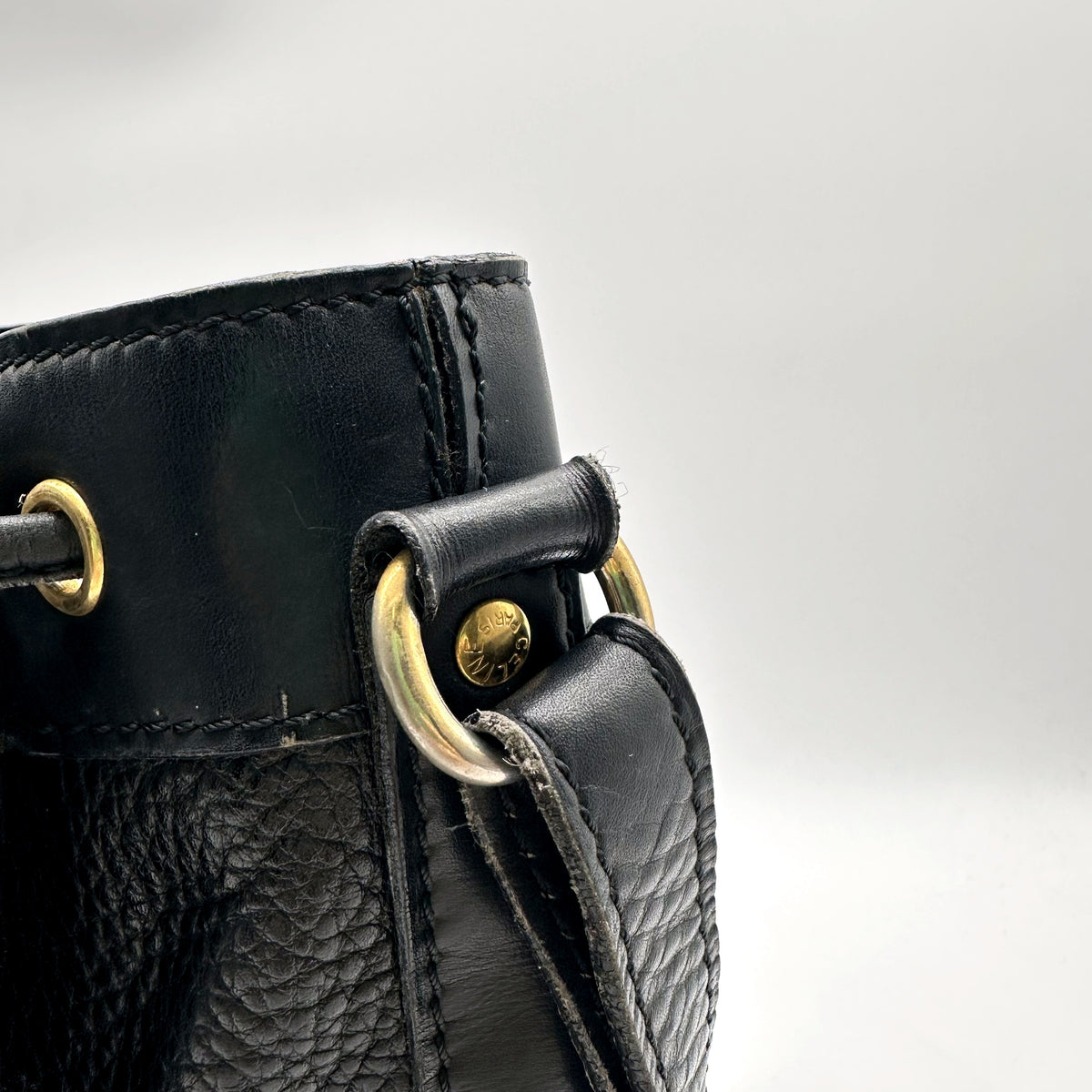 Céline Seau Cuir grainé noir - détail de l'attache de bandoulière et des œillets dorés