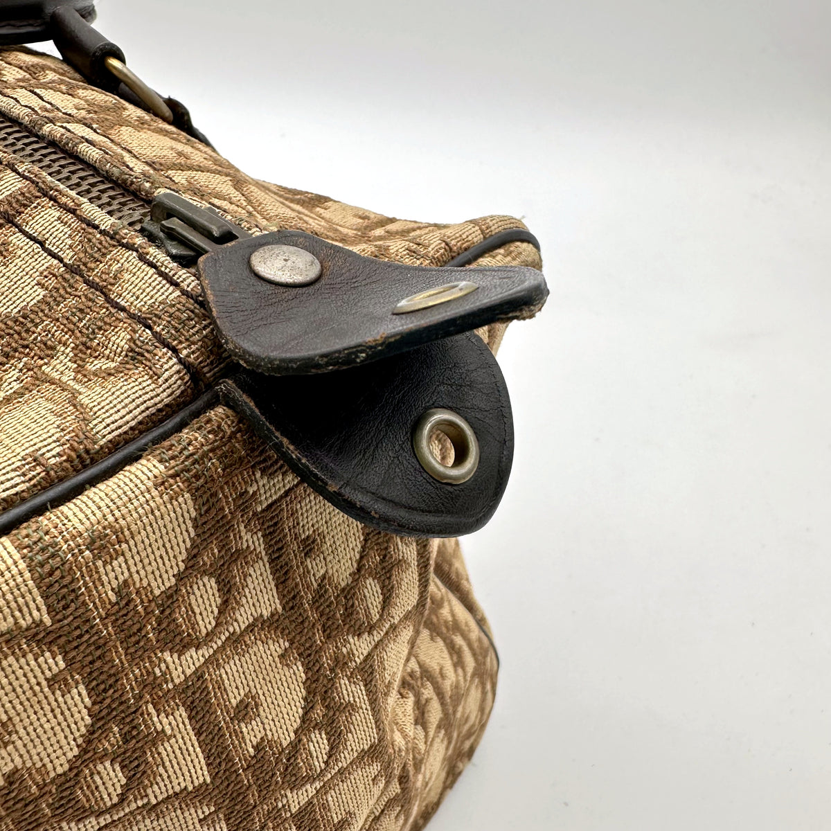 Dior Boston Toile Trotter Beige - détail de la patte de cuir et de l'œillet