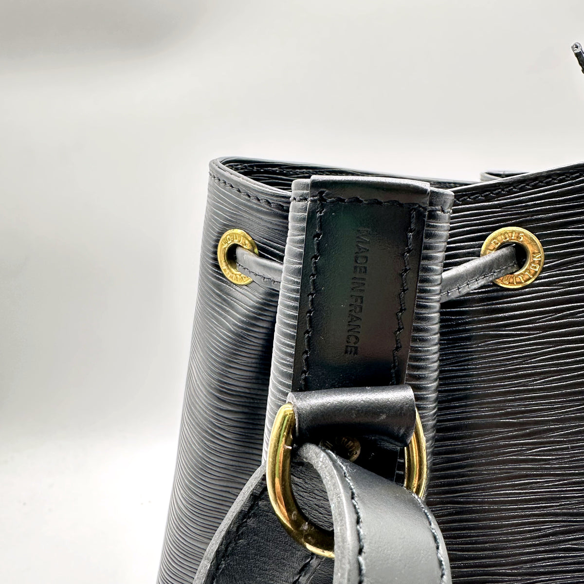 Louis Vuitton Petit Noé Cuir Épi Noir - détail des œillets dorés et de l'attache d'anse