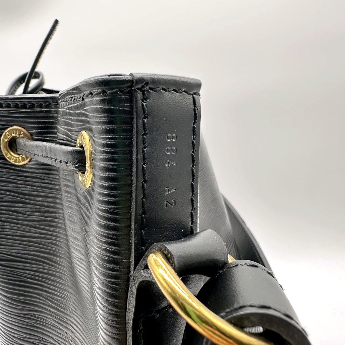 Louis Vuitton Petit Noé Cuir Épi Noir - détail du bord supérieur et de l'anneau doré