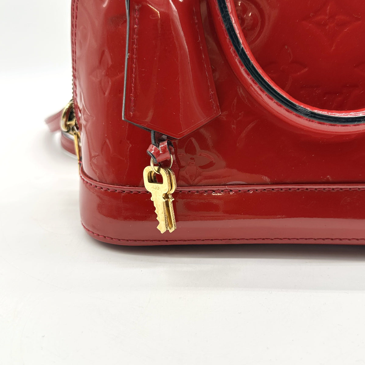 Louis Vuitton Alma BB Cuir Vernis Rouge - détail de la clé et de la patte de cuir