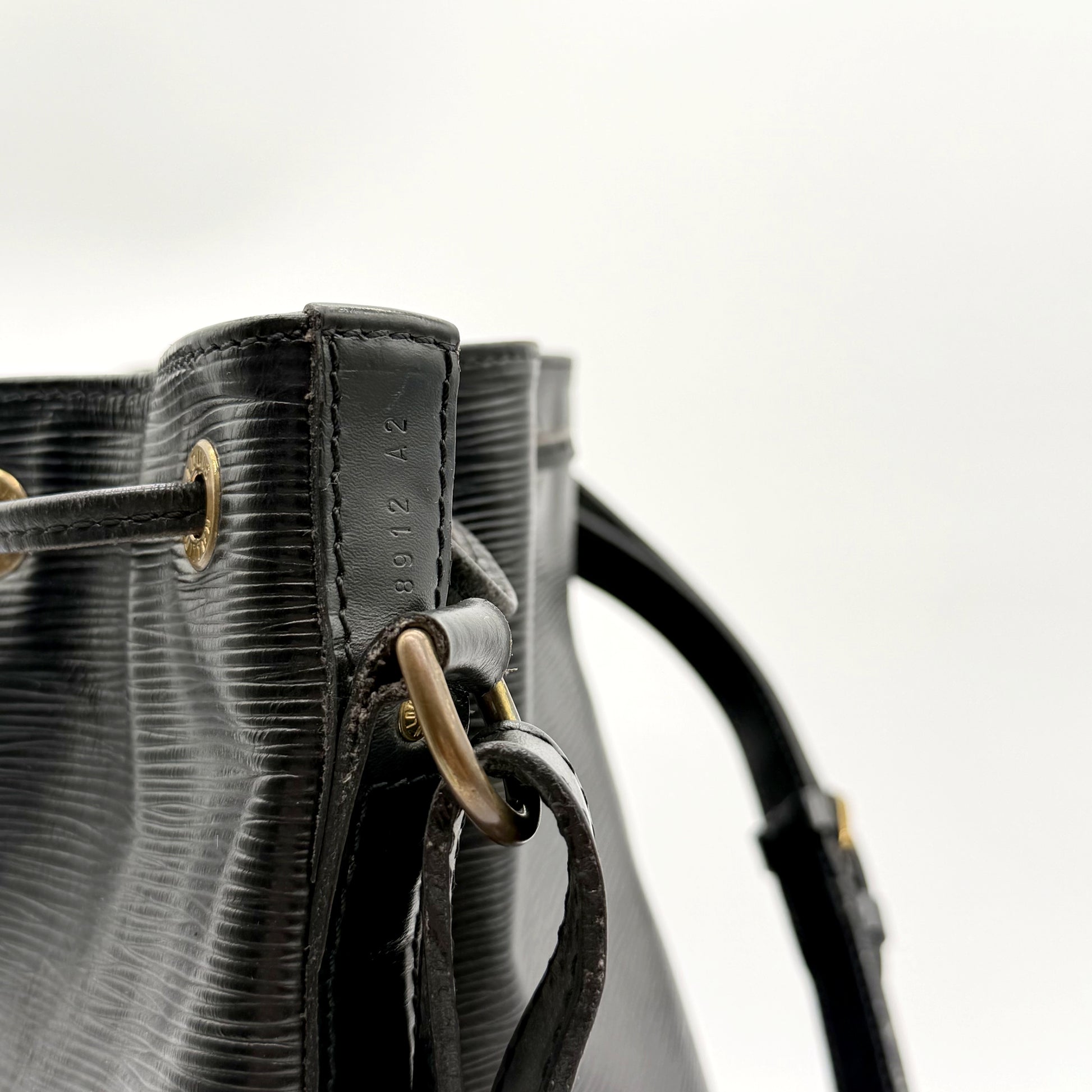 Louis Vuitton Noé Cuir Épi Noir - détail du haut du sac, œillets et attache de bandoulière