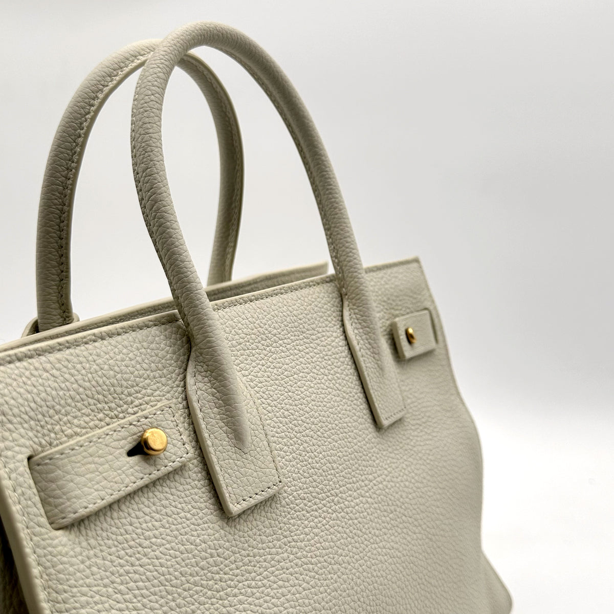 Saint Laurent Sac de Jour Baby Cuir Grainé Blanc Cassé - détail des anses et du bouton de côté