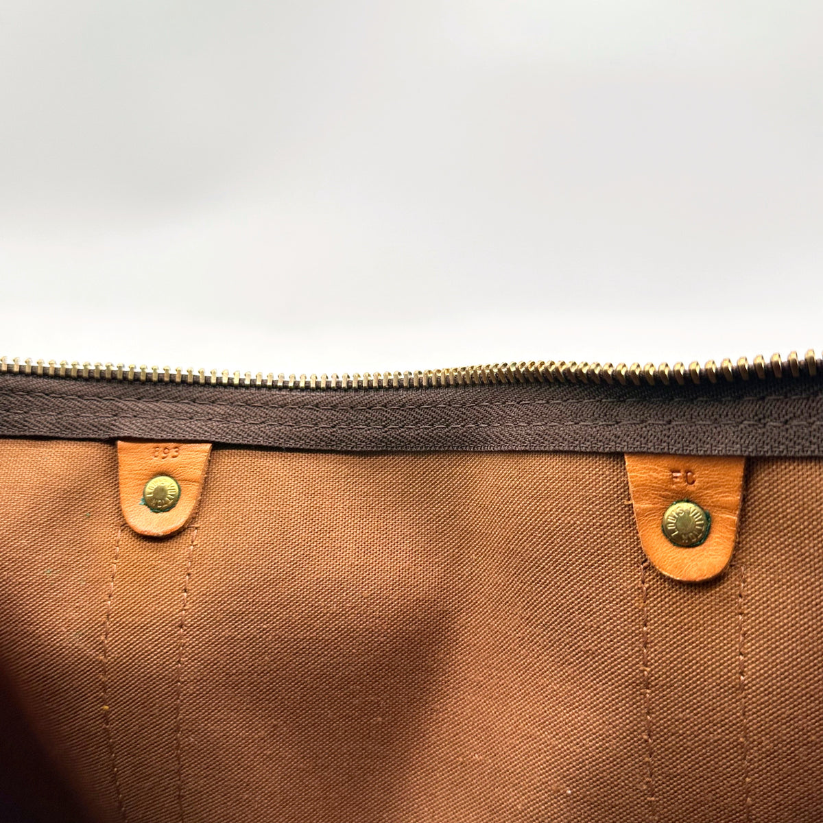Louis Vuitton Keepall Bandoulière 55 Toile Monogram - détail de l'intérieur, pattes de cuir et zip