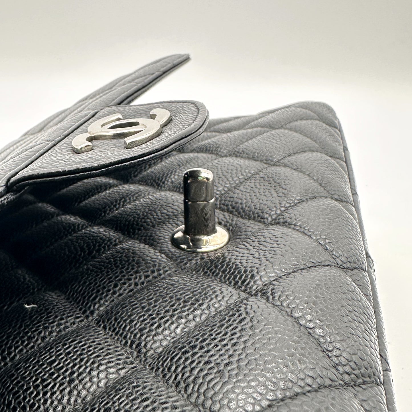 Chanel Timeless 30 cm Cuir Caviar Noir - détail du bouton pression et du haut du sac