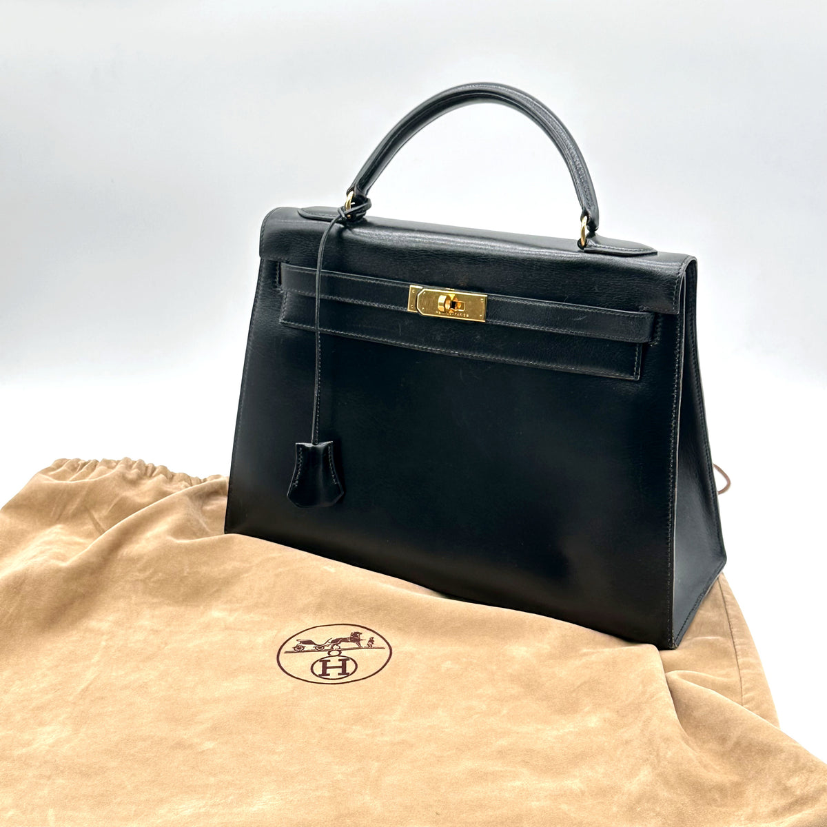 Hermès Kelly 32 Cuir Box Calf Noir - sac posé sur son dust bag d'origine